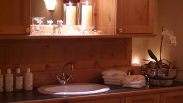 A wooden bathroom vanity with a sink, mirror, and candle holders.