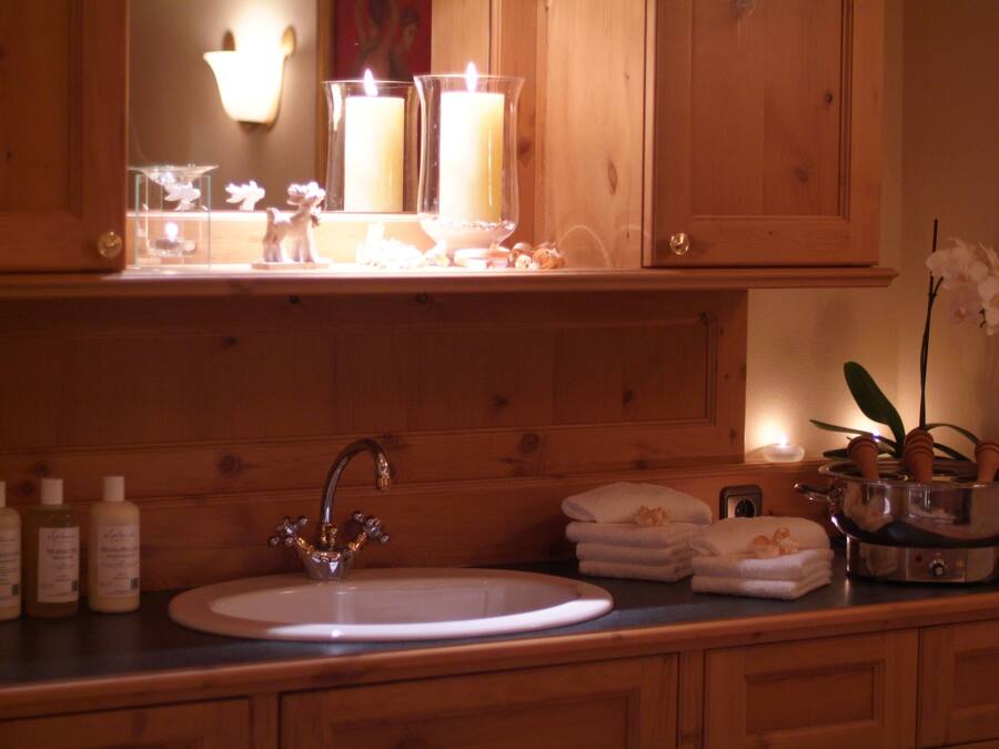 A wooden bathroom vanity with a sink, mirror, and candle holders.