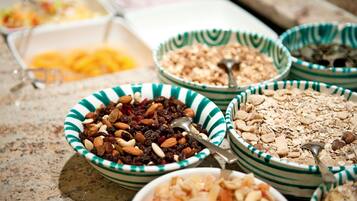 Una variedad de recipientes con diferentes tipos de alimentos, como nueces, frutas secas y cereales, dispuestos sobre una encimera.