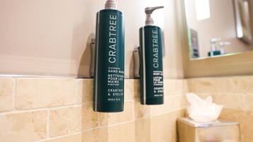 Two hand wash bottles of Crabtree & Evelyn soap on a beige tiled wall.