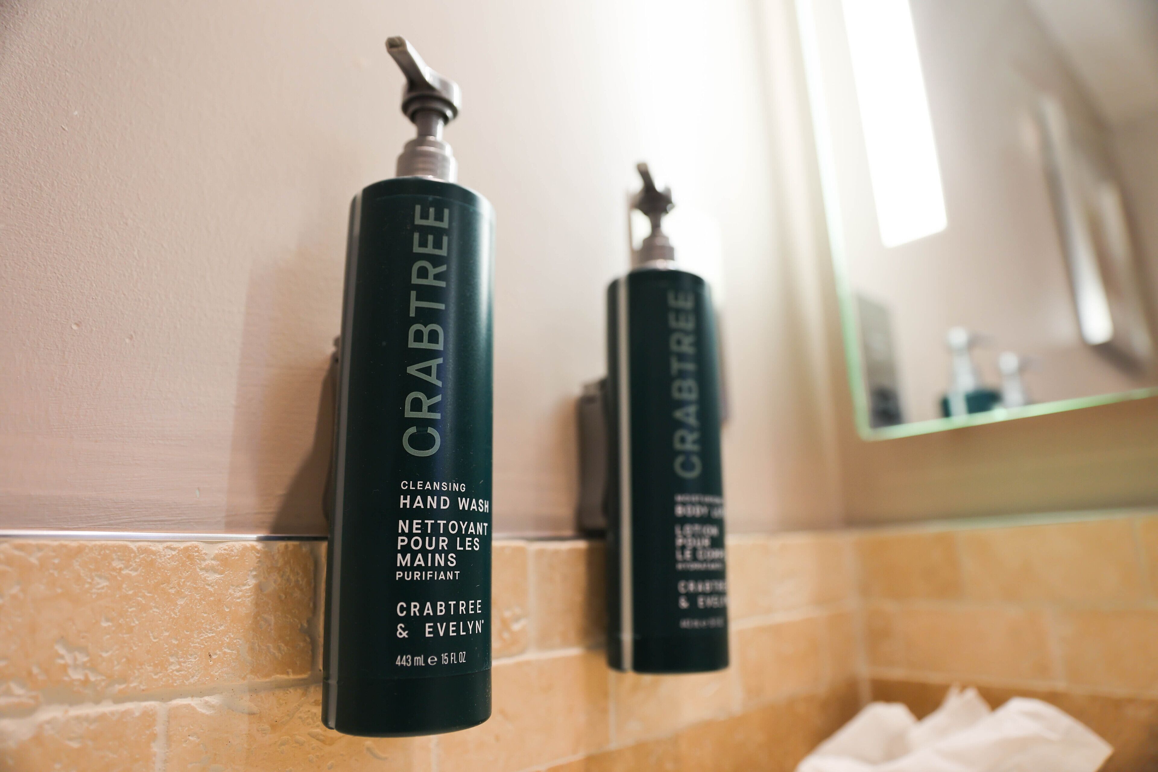 Dos botellas de jabón líquido para manos Crabtree & Evelyn sobre una encimera de baño.