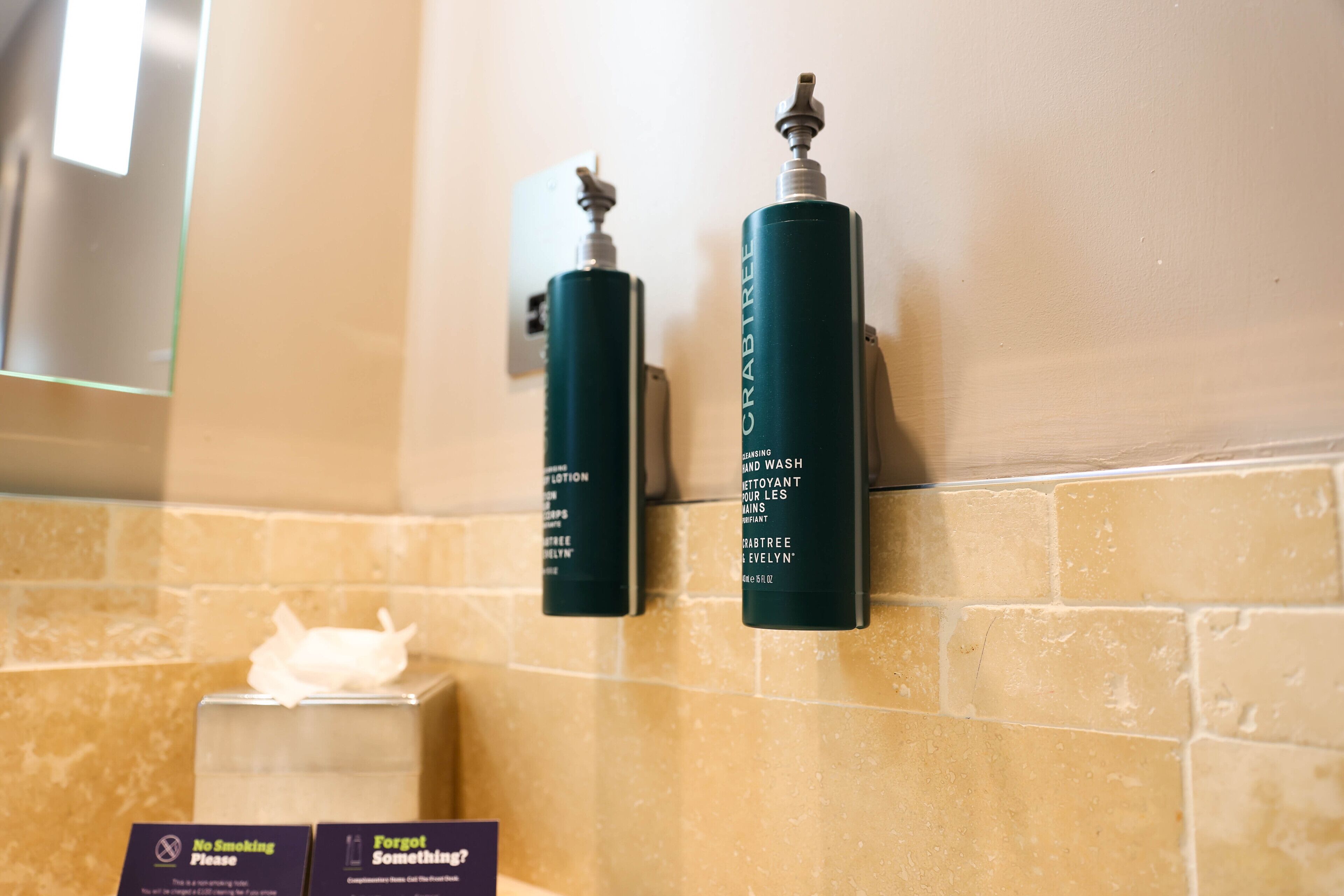 Two hand sanitizer dispensers labeled 'CRABTREE' mounted on a wall with a 'No Smoking' sign and a 'Forgot Something?' sign below them.