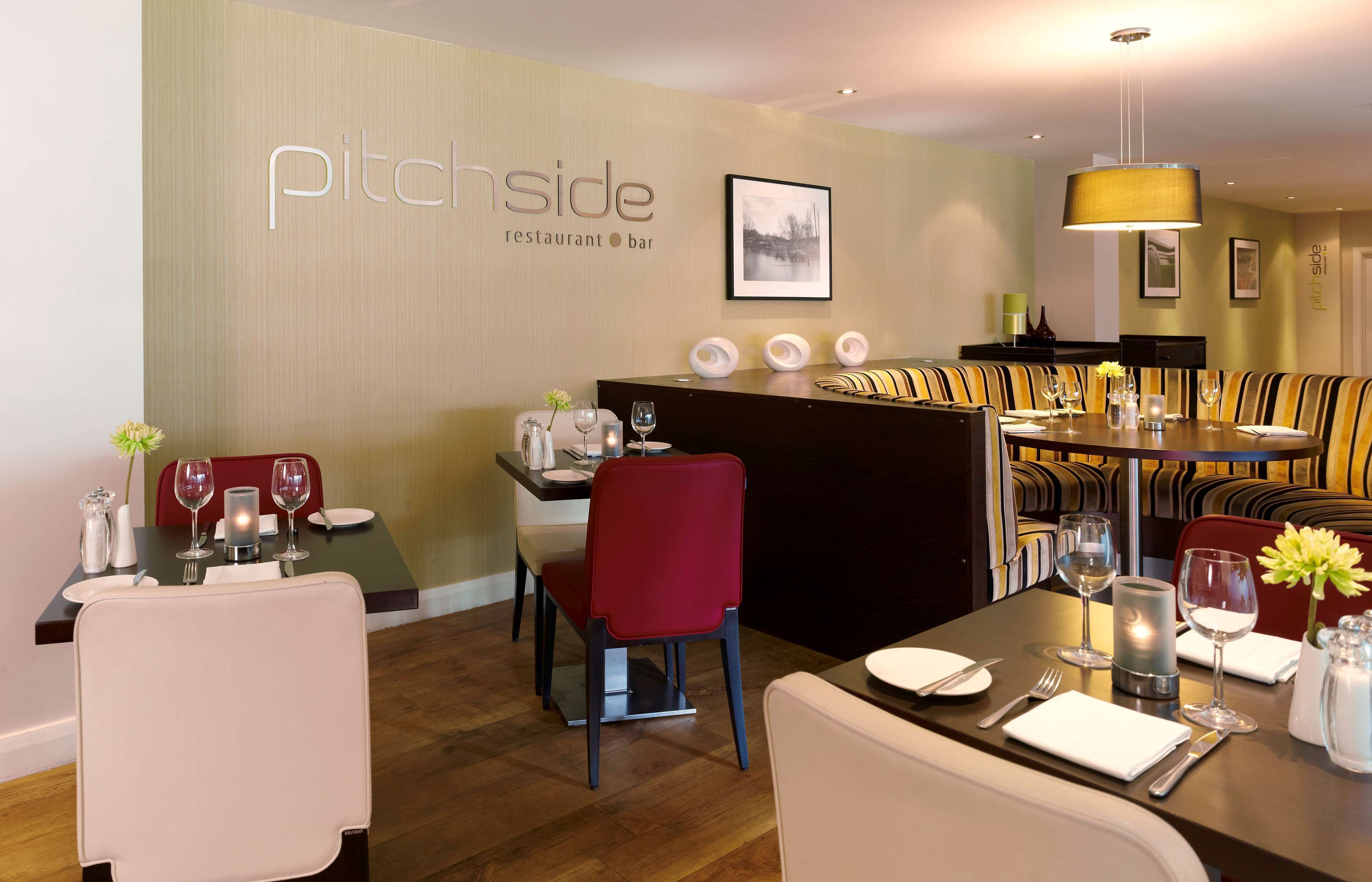 A restaurant with a modern interior, featuring a dining area with tables and chairs, a bar area, and a wall with the restaurant's name.