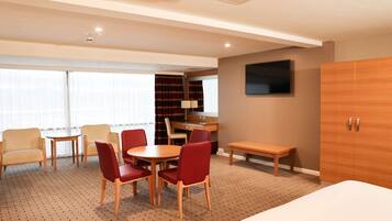 A hotel room with a bed, a desk, a chair, a table, and a TV.