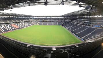 A large stadium with multiple tiers of seating and a central field.