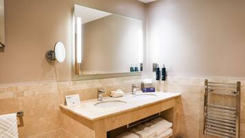 A bathroom with two sinks, a large mirror, a towel rack, and a trash can.