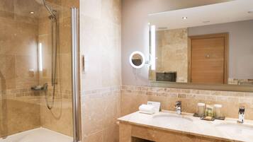 A modern bathroom with a glass-enclosed shower, a large mirror, and a vanity with two sinks and toiletries.