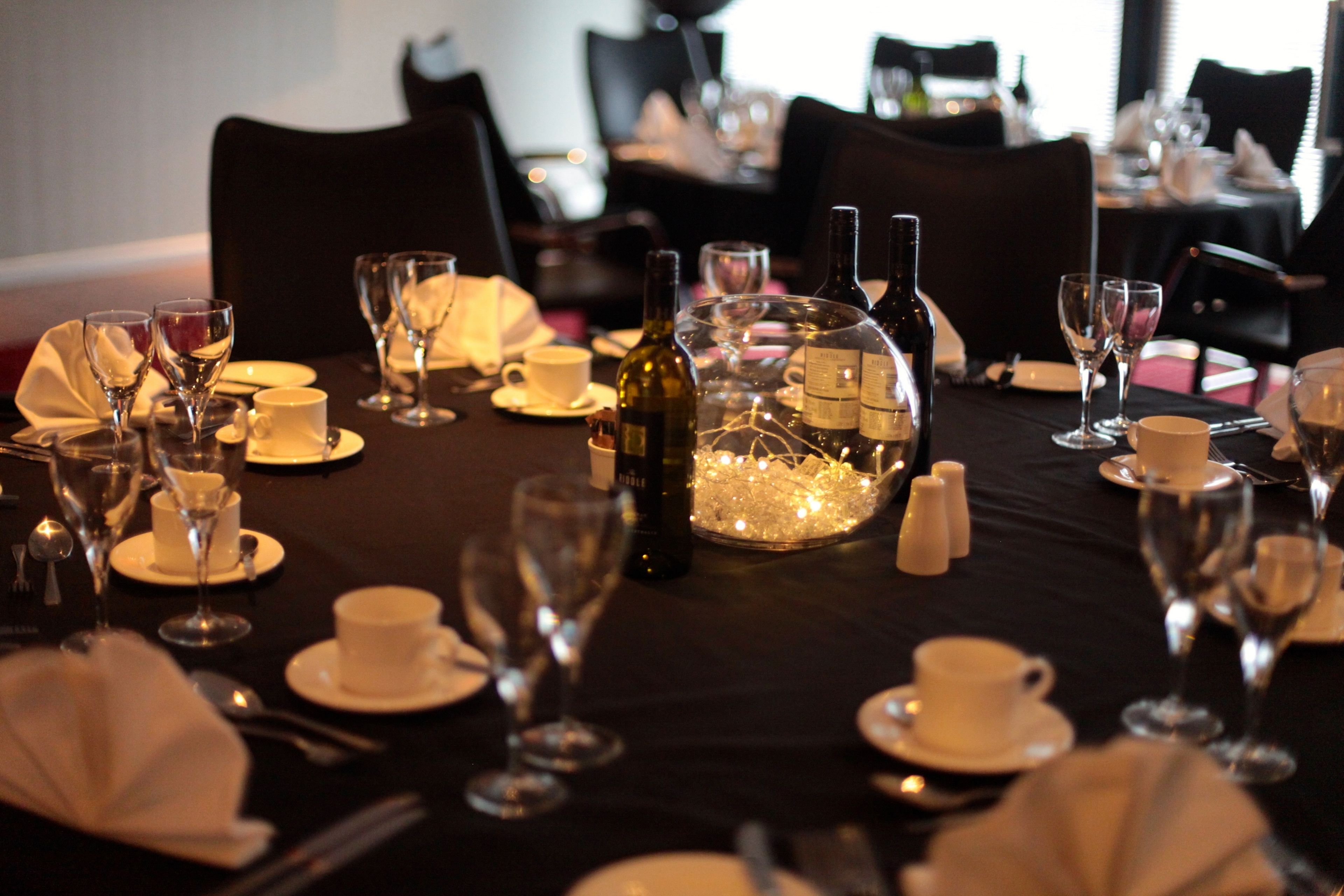 A dining table set for a meal with wine glasses, bottles, and a centerpiece.