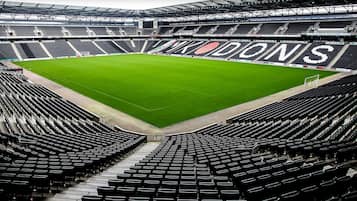 Un estadio con césped verde y asientos negros.