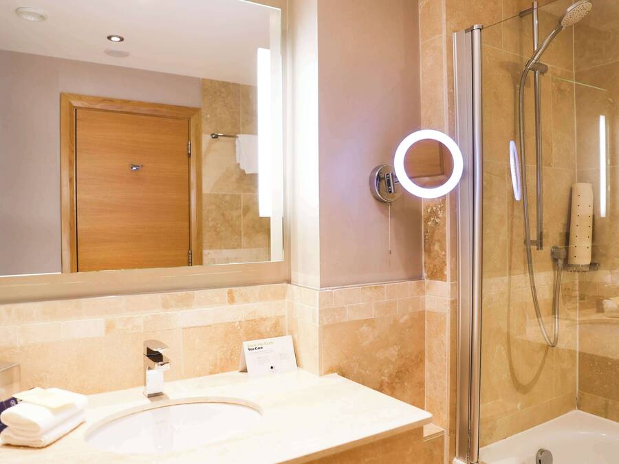 A bathroom with a sink, mirror, and glass-enclosed shower.
