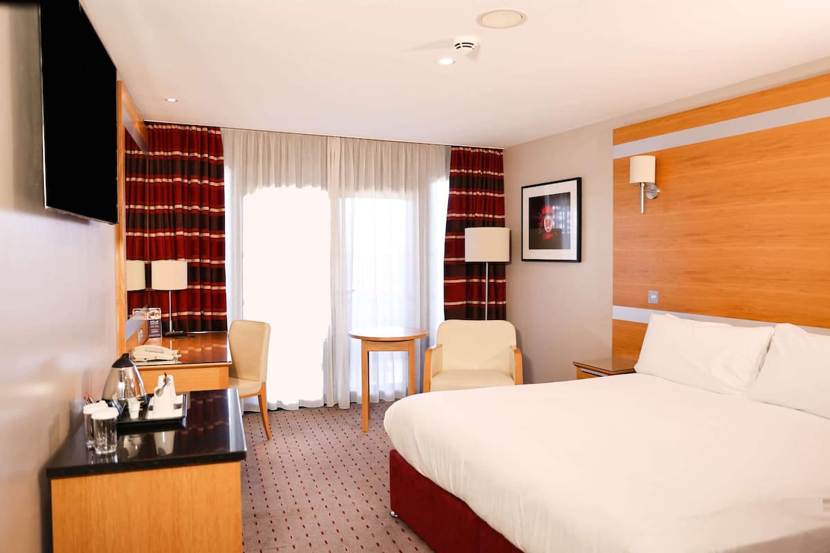 Une chambre d’hôtel avec un lit, un bureau, une chaise et une petite table.