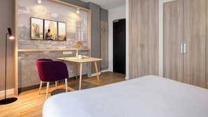 A modern hotel room with a bed, a desk, a chair, and a wardrobe. - Citadines Arnulfpark Munich (Munich)