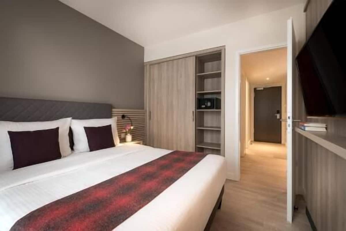 A bedroom with a bed, a wardrobe, and a door leading to another room.