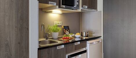 A compact kitchen with a microwave, sink, and dishwasher.