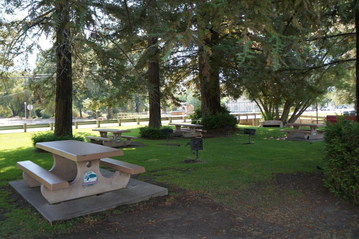 A park with picnic tables and benches, surrounded by trees.