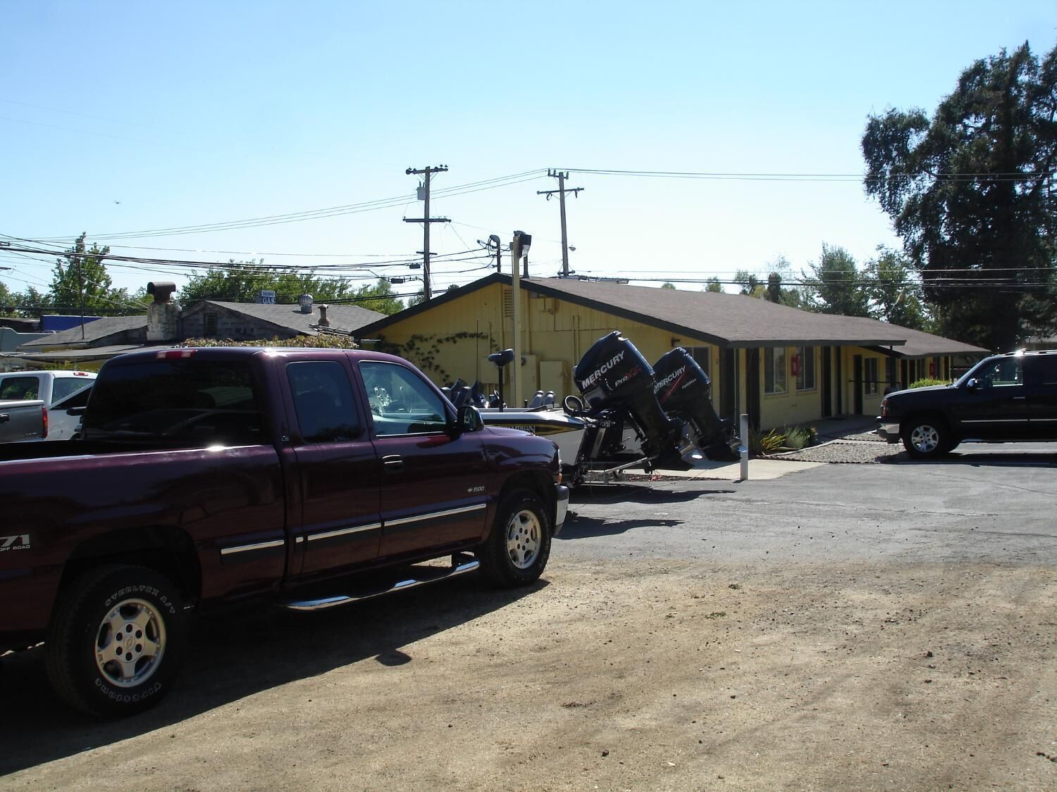 A parking lot with a maroon pickup truck and a motorcycle with Mercury branding.