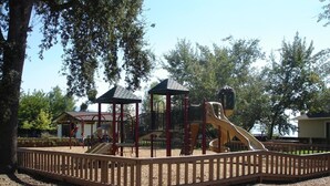 A playground with a wooden fence, a slide, and a climbing structure.