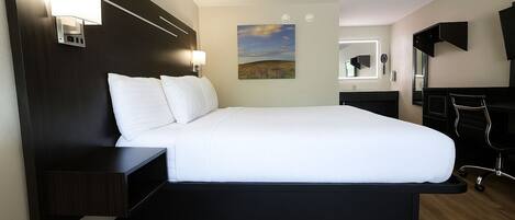 A modern hotel room with a large bed, a desk, and a TV.