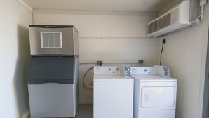 A compact laundry room with a stainless steel refrigerator, a washing machine, and a dryer. - Paragon Inn Hillsboro (Hillsboro)
