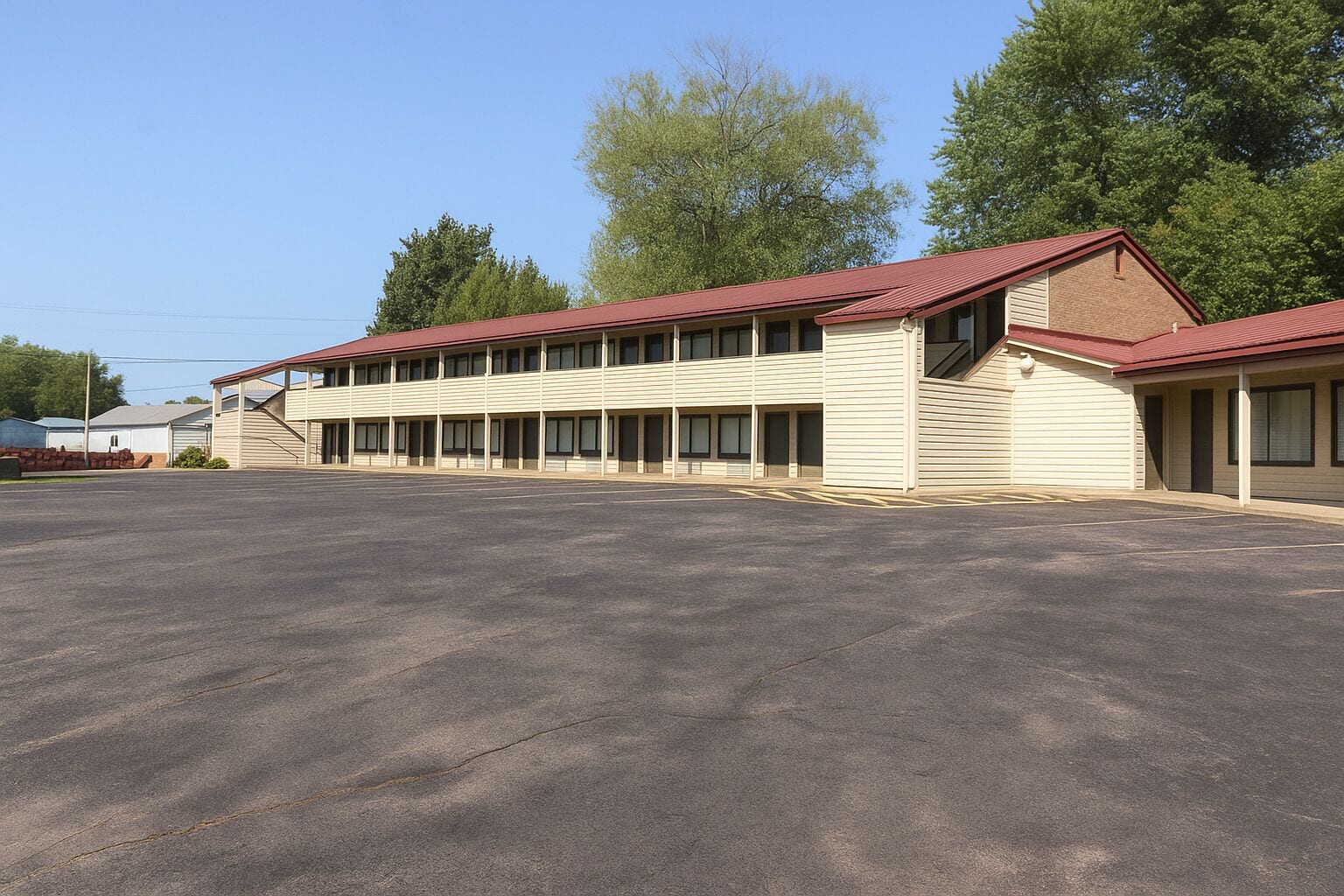 A large, single-story building with a red roof and beige siding, featuring a long row of windows and a spacious parking lot.