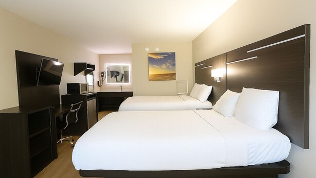 A hotel room with two beds, a TV, a desk, and a mirror. - Paragon Inn Hillsboro (Hillsboro)