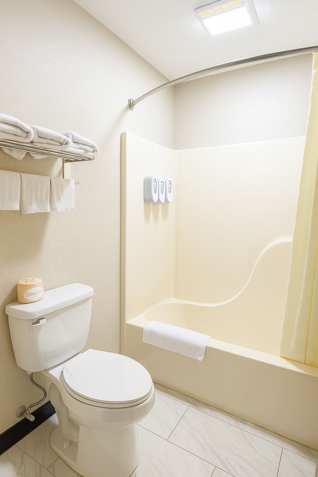 Une salle de bain comprenant des toilettes, une douche avec une porte en verre et un porte-serviettes avec des serviettes pliées.