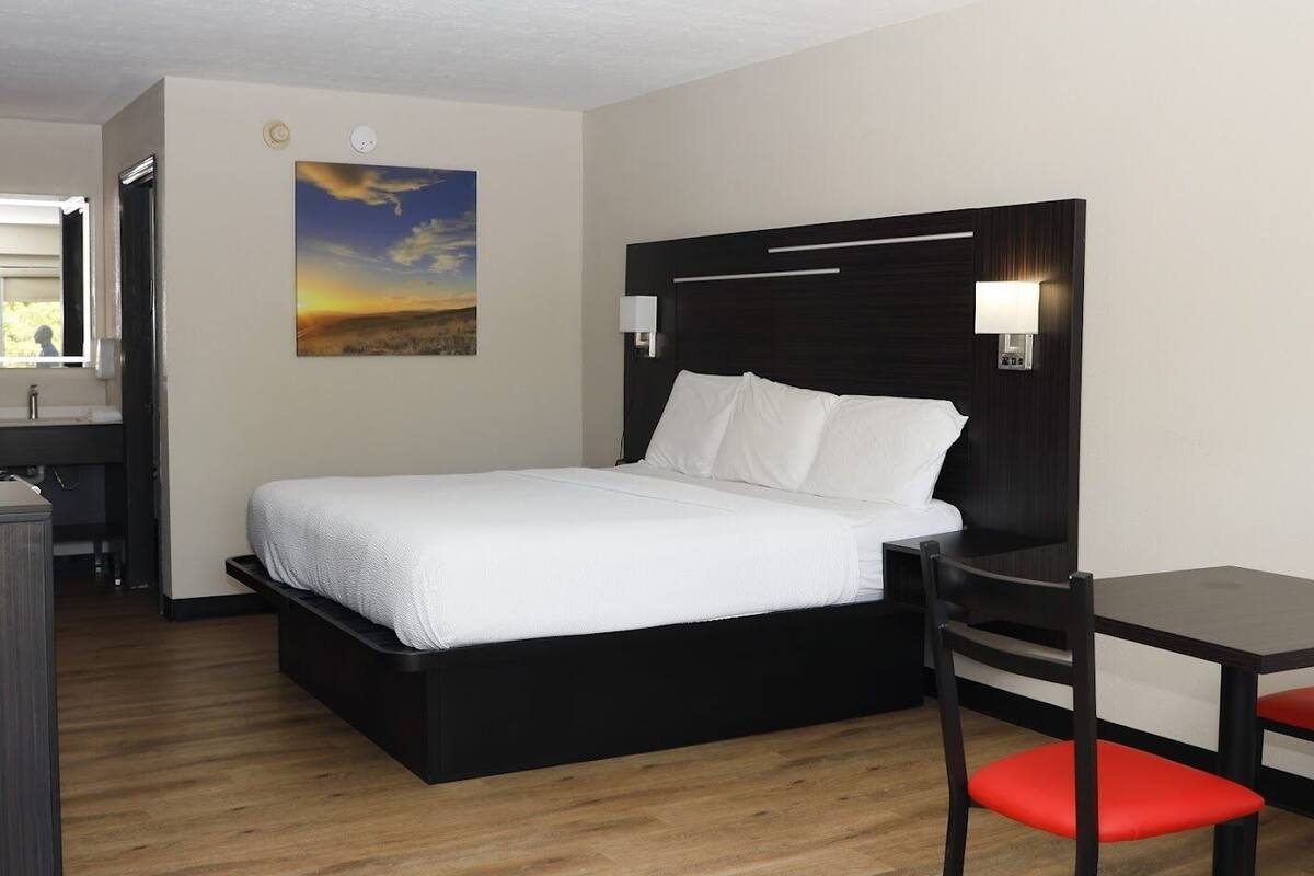 A hotel room with a bed, a desk, and a chair.