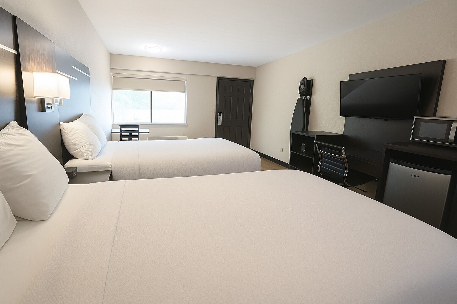 Habitación de hotel con dos camas, un escritorio, un televisor y un refrigerador.