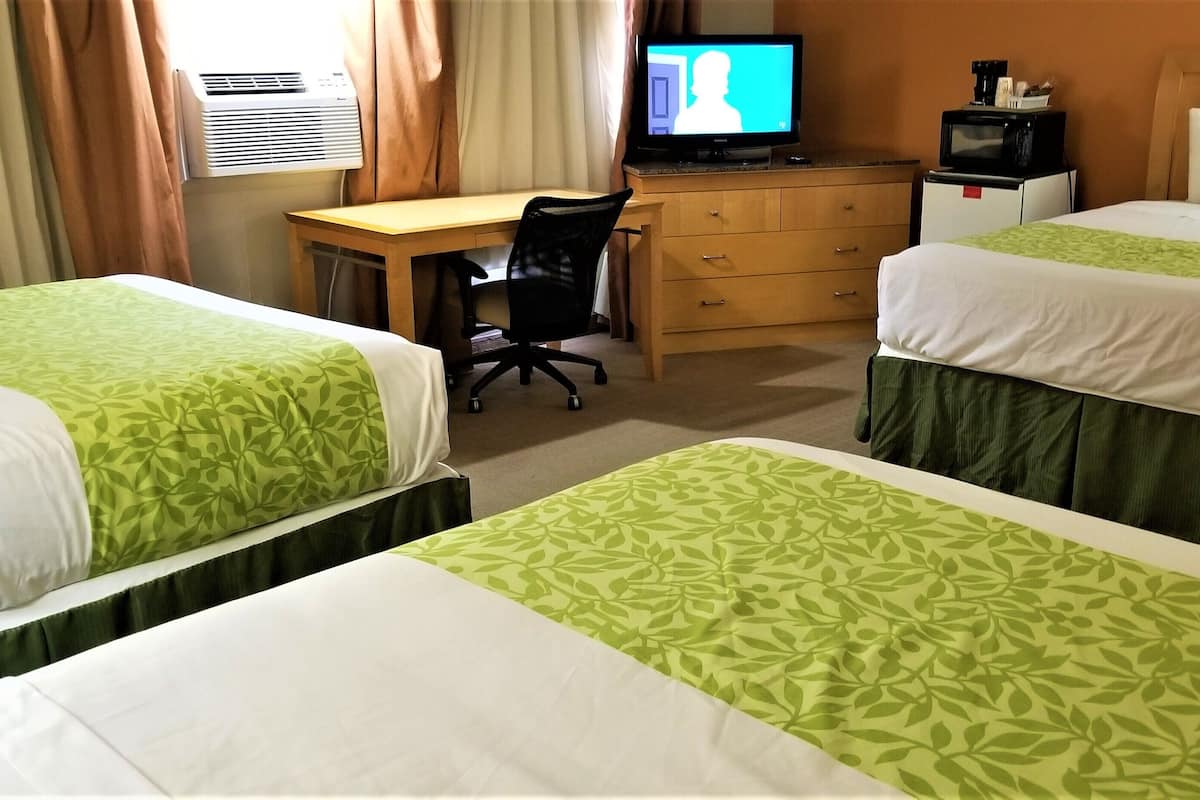 A hotel room with two beds, a desk, a television, and a microwave.