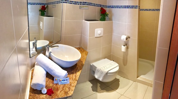 Un baño con lavamanos, espejo, inodoro y ducha.
