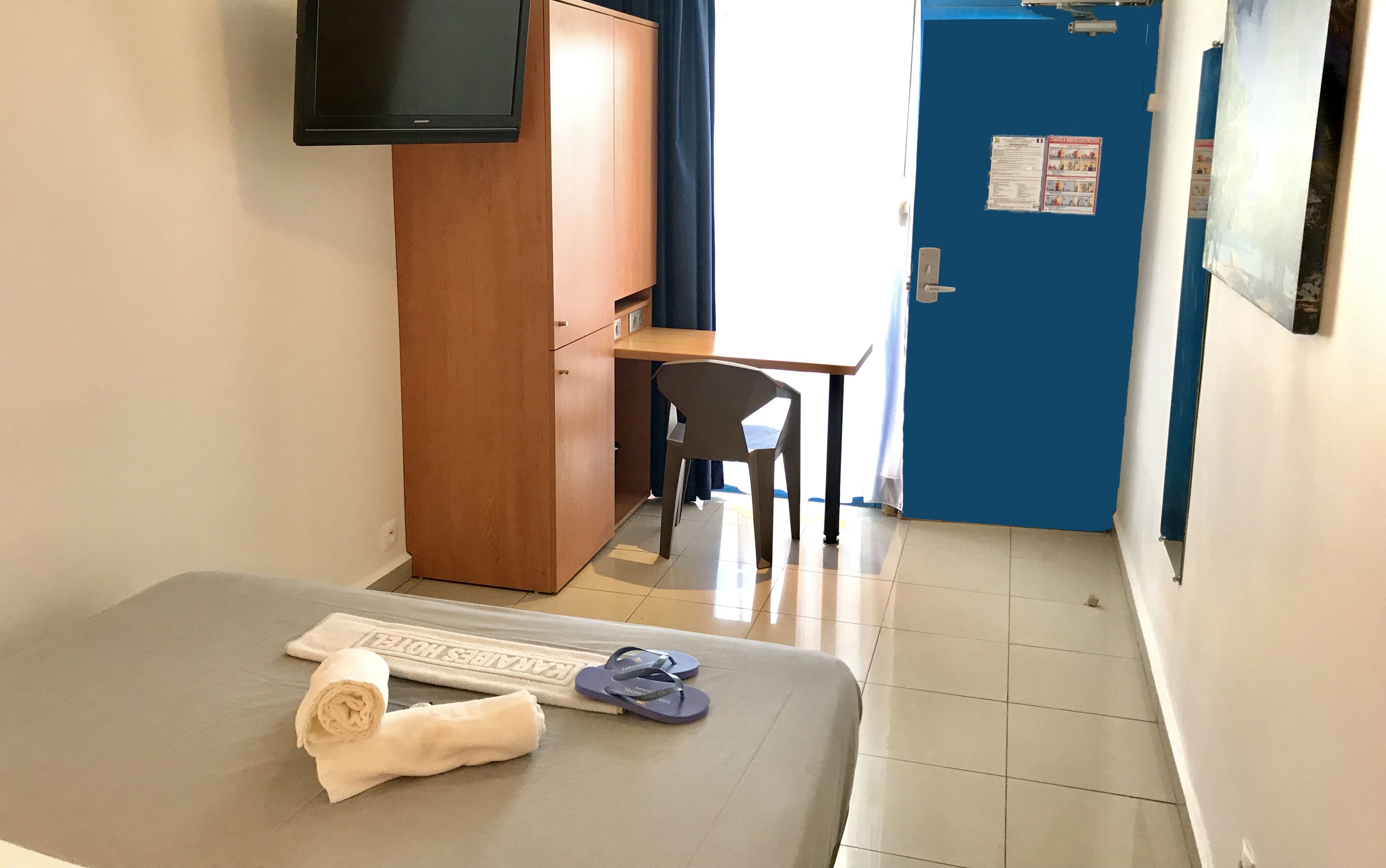 Une chambre d’hôtel comprenant un lit, un bureau, une chaise, une armoire et un téléviseur.
