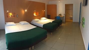 Une chambre d’hôtel avec trois lits, un bureau et une salle de bain.