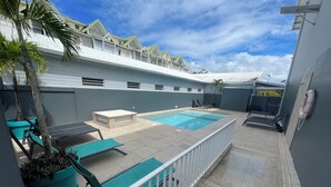 A rooftop pool area with a pool, lounge chairs, and a small seating area. - Karaibes Hotel (Le Gosier)
