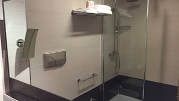 A modern bathroom with a glass-enclosed shower, a toilet, and a sink.