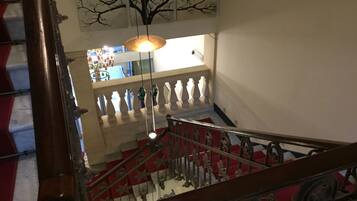 A staircase with a red and white striped railing, a wooden handrail, and a hanging light fixture.