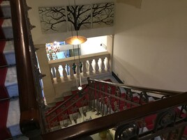 A staircase with a red and white striped railing, a wooden handrail, and a hanging light fixture.