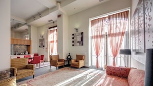 A spacious living room with a large sofa, two armchairs, a dining area with a table and chairs, and a kitchen in the background.