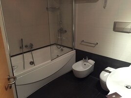 Ein modernes Badezimmer mit einer Duschkabine, einer weißen Badewanne, einem Bidet und einer Toilette.