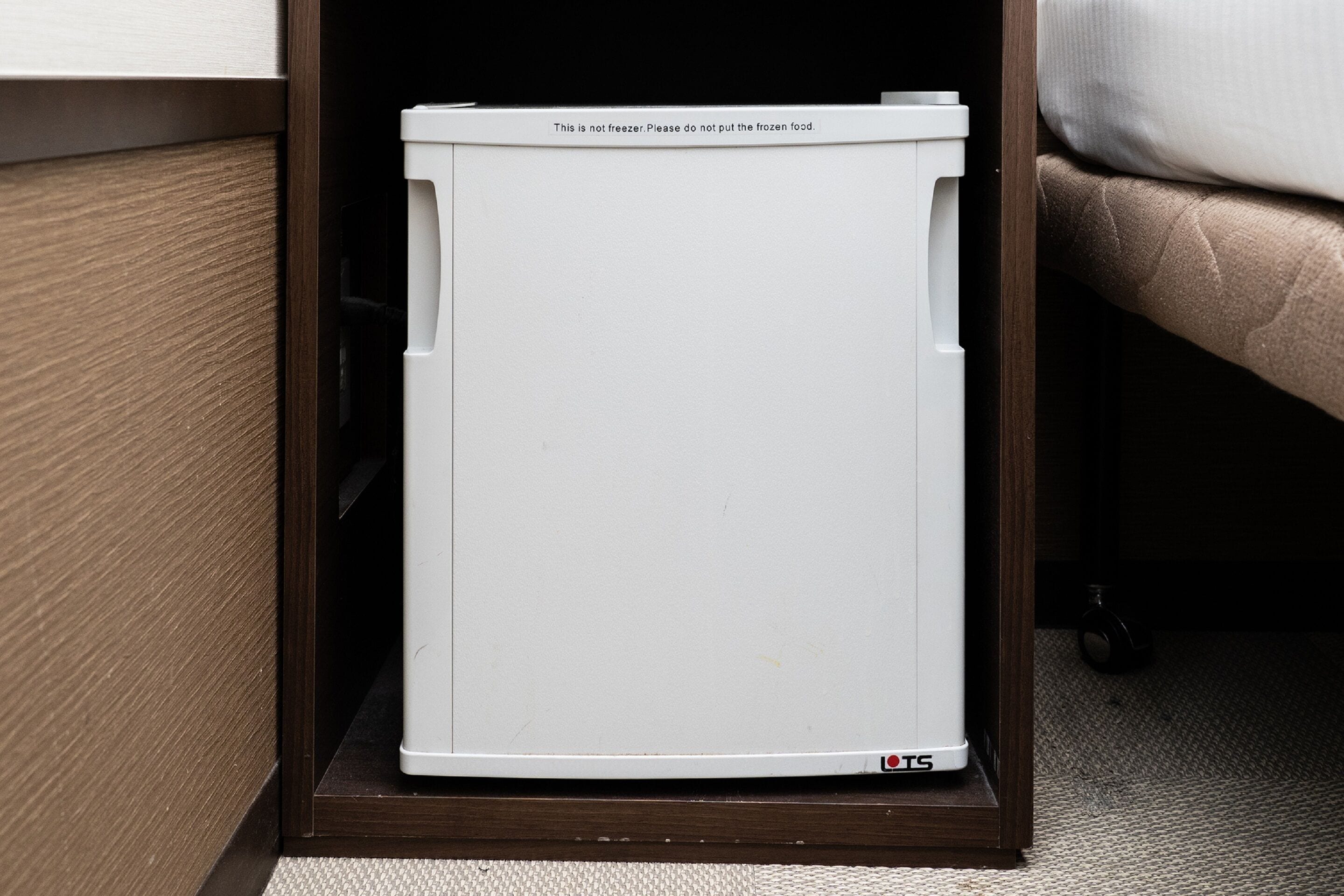 Un electrodoméstico blanco con una etiqueta de advertencia en un gabinete de madera.