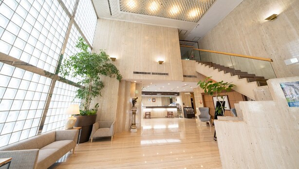 A spacious lobby with a high ceiling, a staircase, and a reception desk. - Hotel Sunlite Shinjuku (Tokyo)