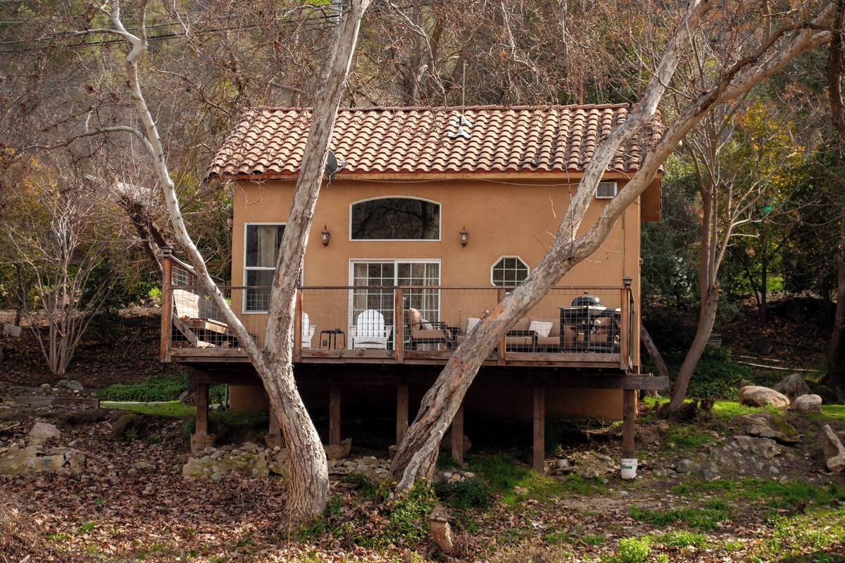 Una casa con techo de tejas, ventanas amplias y una terraza con mobiliario exterior.