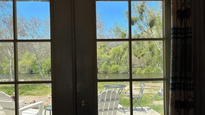 Vista a través de un ventanal con mesas al aire libre y un río.