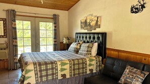 Un dormitorio con una cama grande, un sofá de cuero negro y una ventana con cortinas.