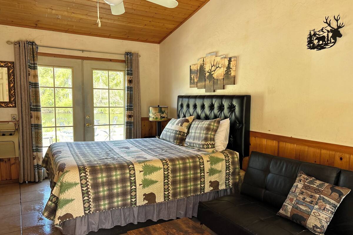 Un dormitorio con una cama grande, un sofá de cuero negro y una ventana con cortinas.