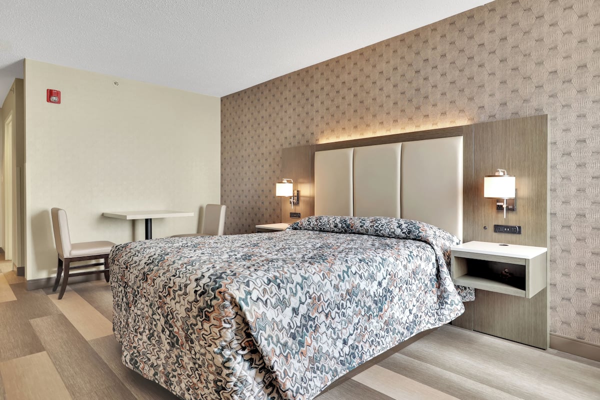 A hotel room with a large bed, a desk, and two bedside lamps.