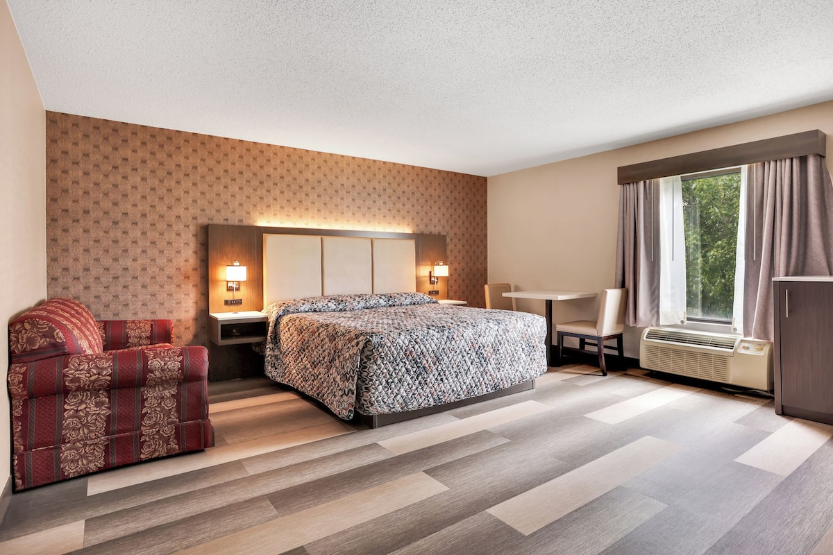A hotel room with a bed, a sofa, a desk, and a window with curtains.