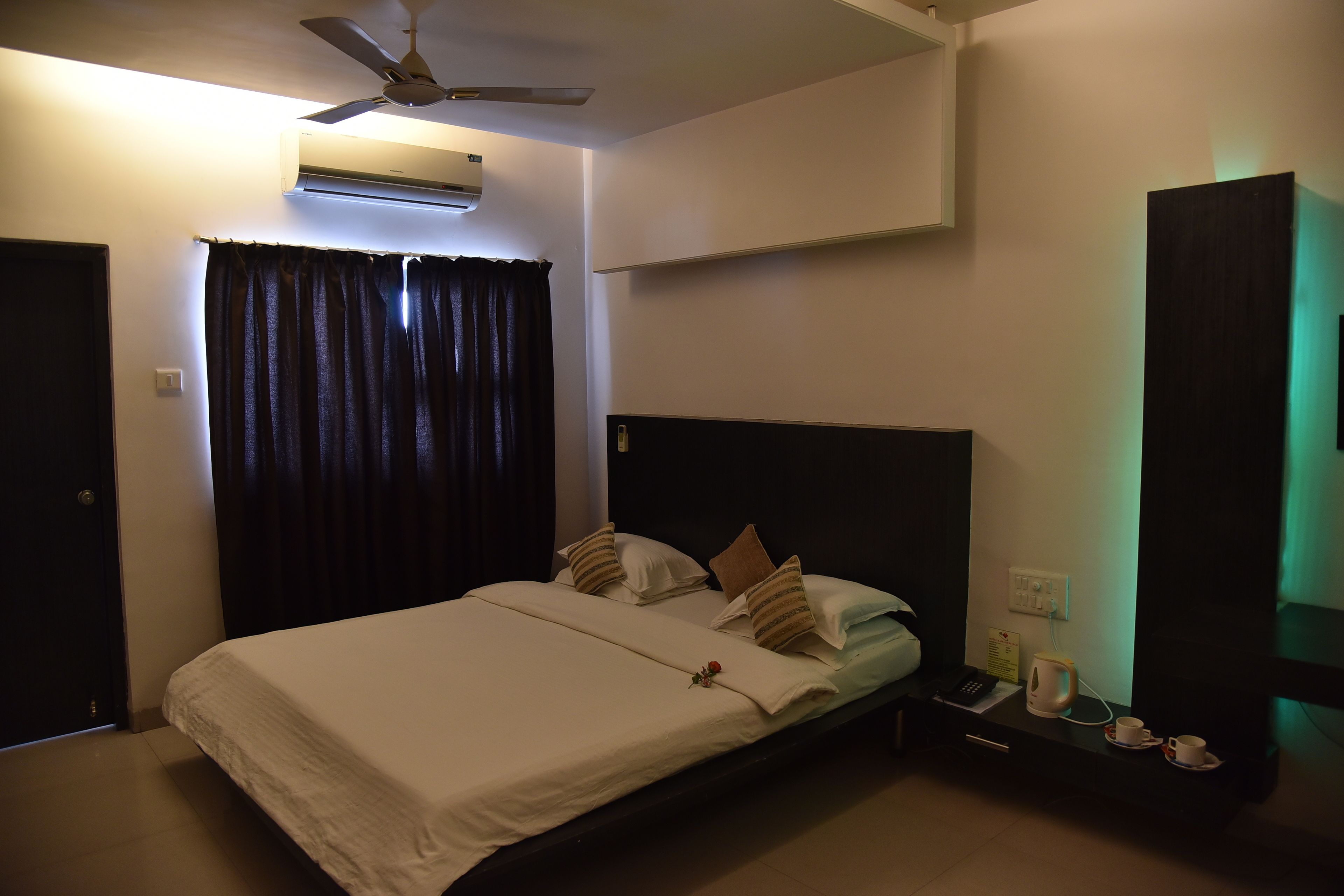 Habitación de hotel con cama, mesita de noche, teléfono, taza y tetera.