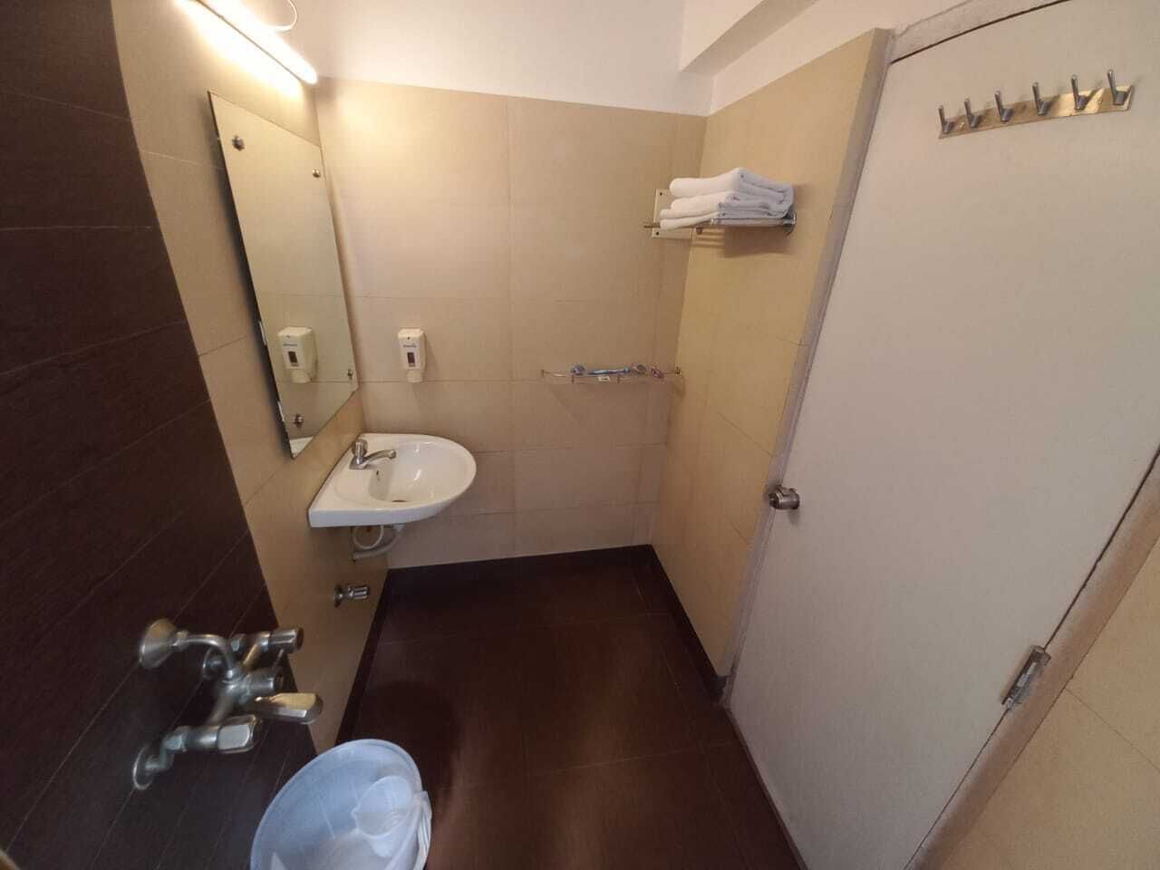 Un baño pequeño con lavamanos, espejo, toallero y una puerta.