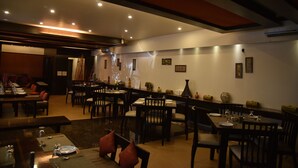 Un restaurante con varias mesas y sillas, una barra larga y una pared decorada con cuadros.