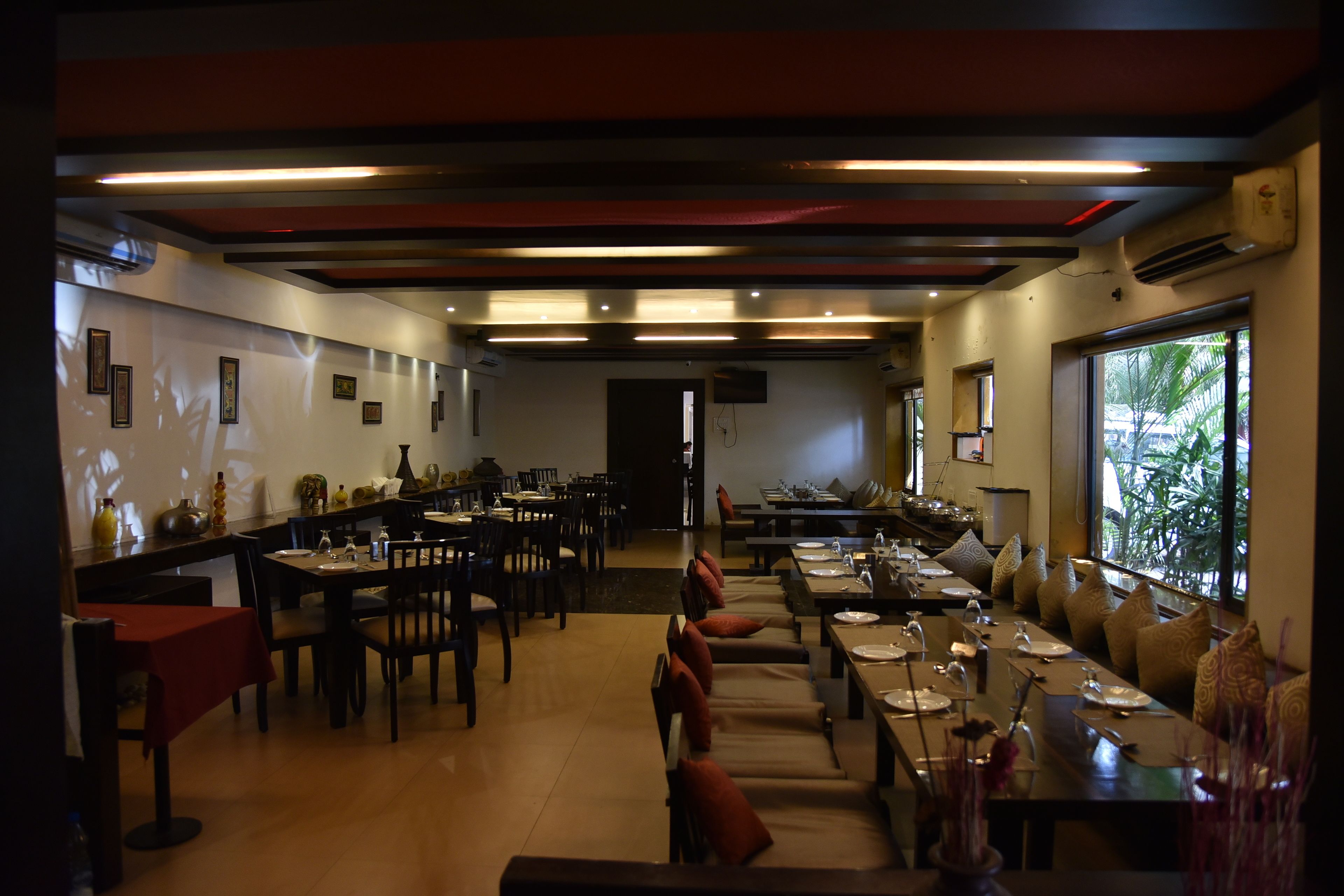 A restaurant with multiple dining areas, including a long communal table and smaller tables.